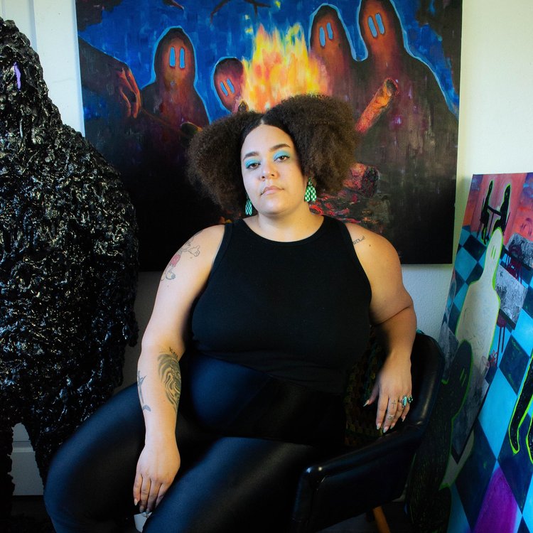 Artist seated in The LINE Austin’s gallery space, surrounded by bold contemporary works and sculptural installations.