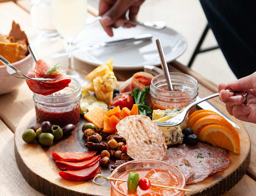 a charcuterie plate with a variety of cured meat, jams, fermented vegetables, and fruit