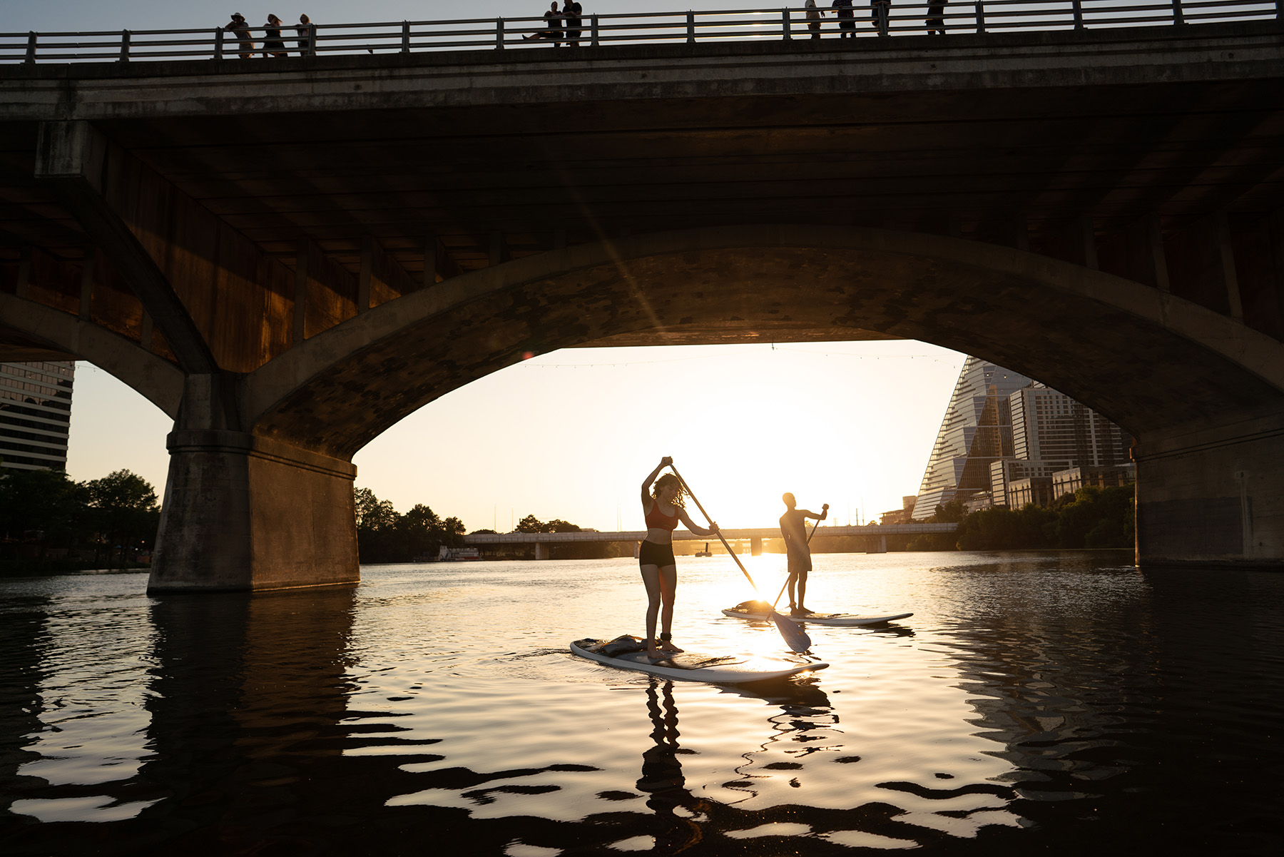 Two people stand-up paddle boarding around Lady Bird Lake in Austin, Texas.
