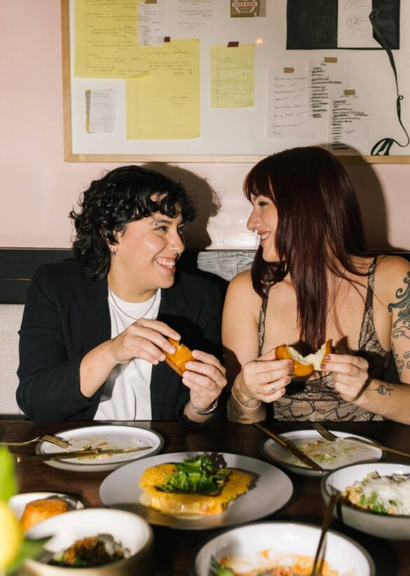 two women smiling at each other while eating