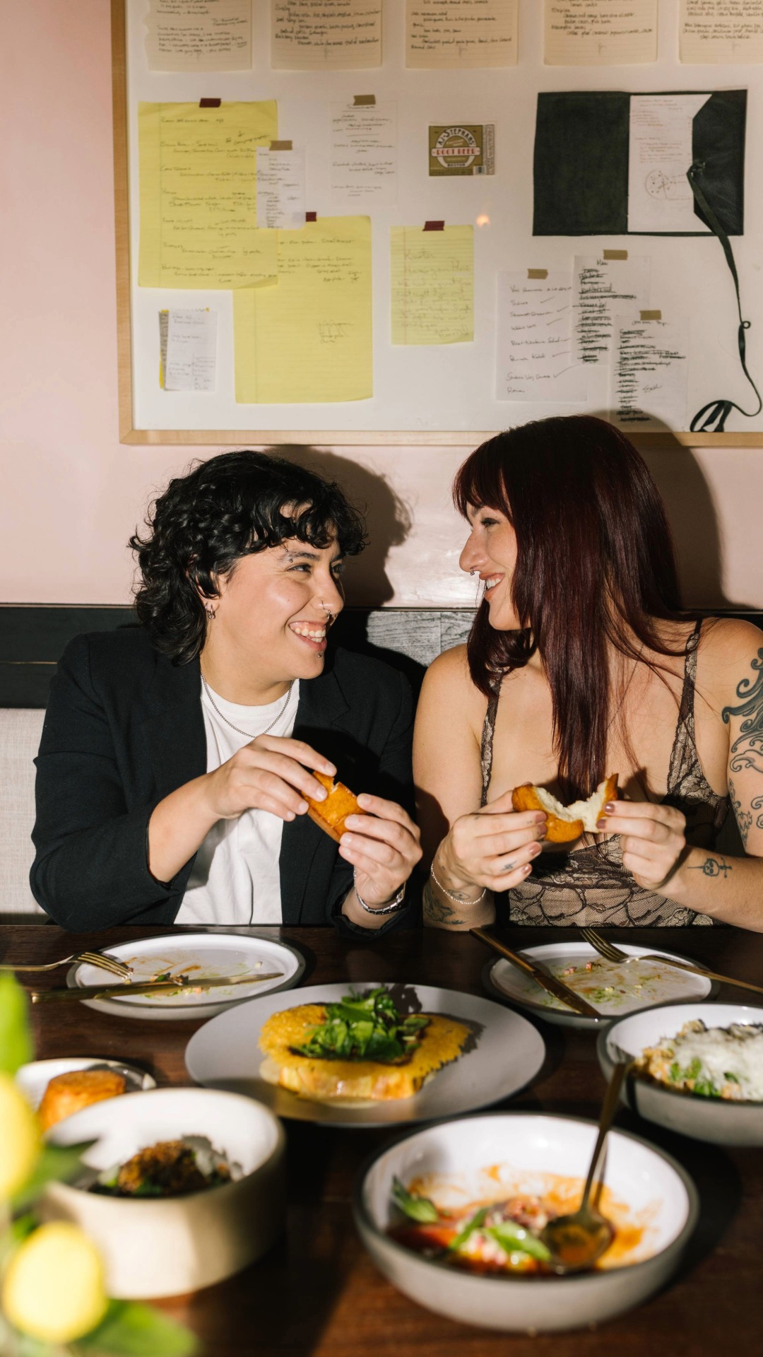 two women smiling at each other while eating