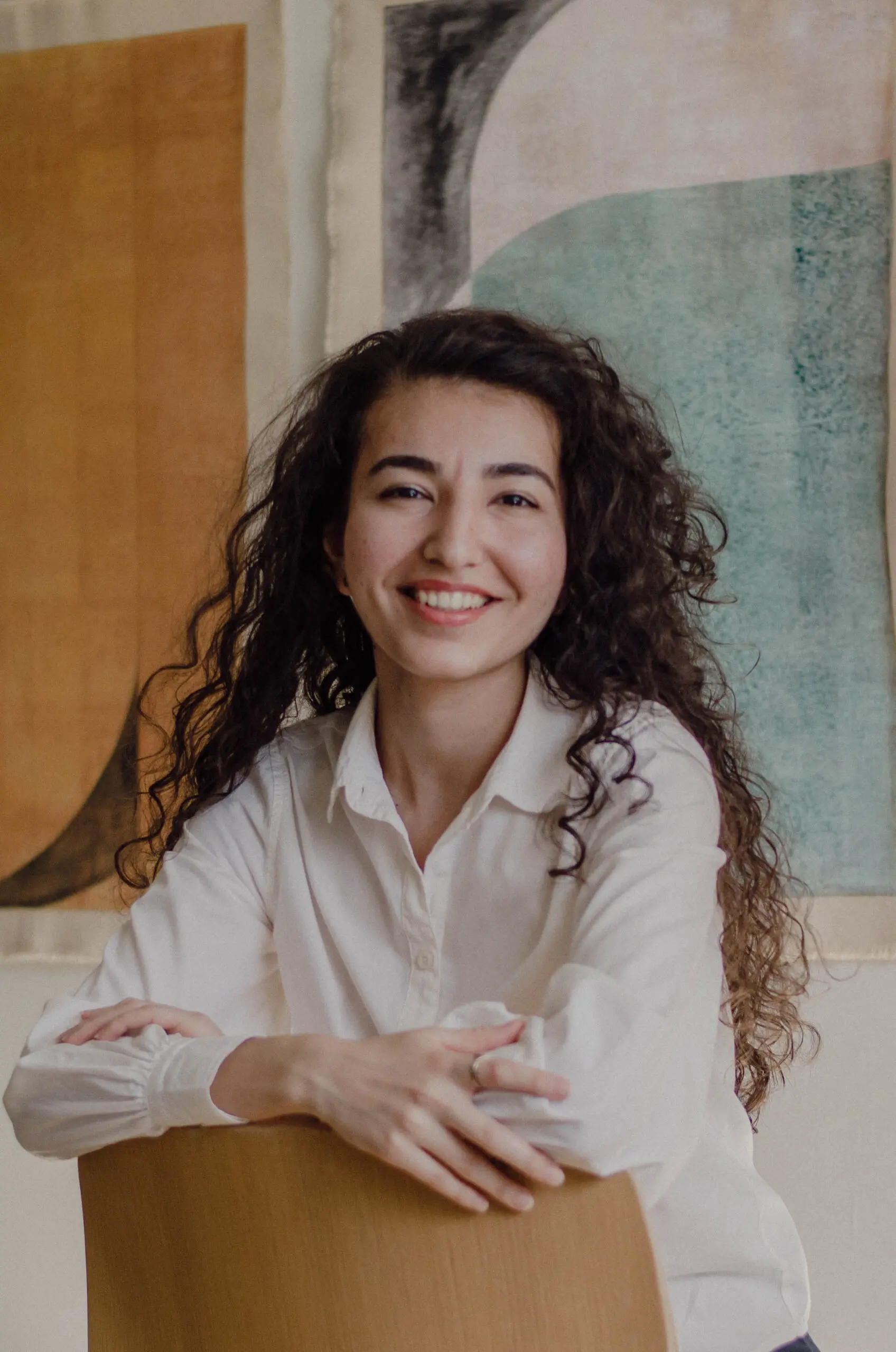 A curly hair girl looking at the camera smiling.