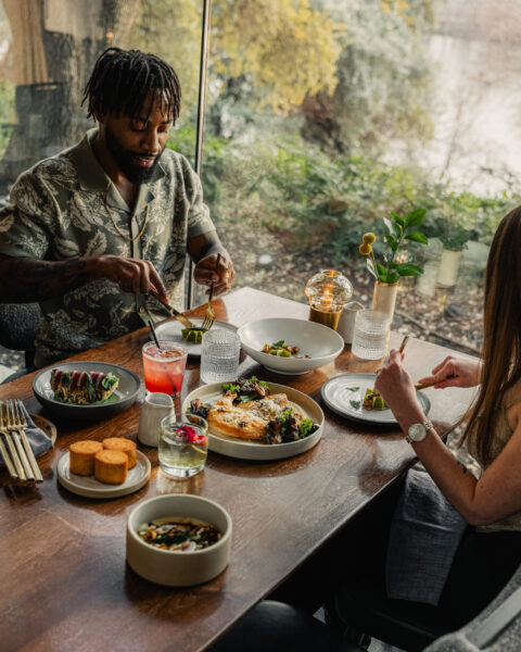 Two friends enjoying drinks and food at a cozy restaurant table