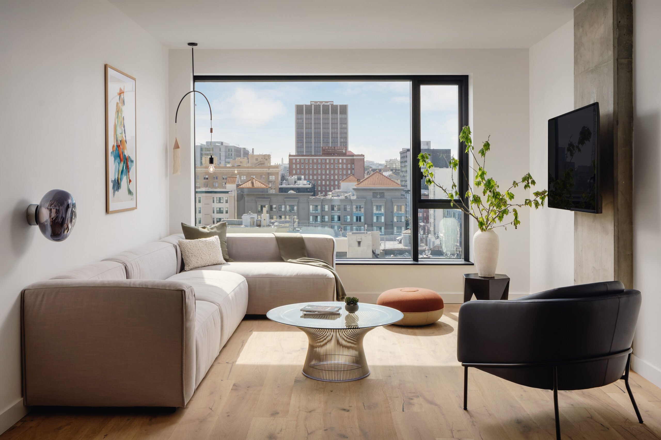 A L-shaped couch positioned near the glass window offers a wonderful view of the city.