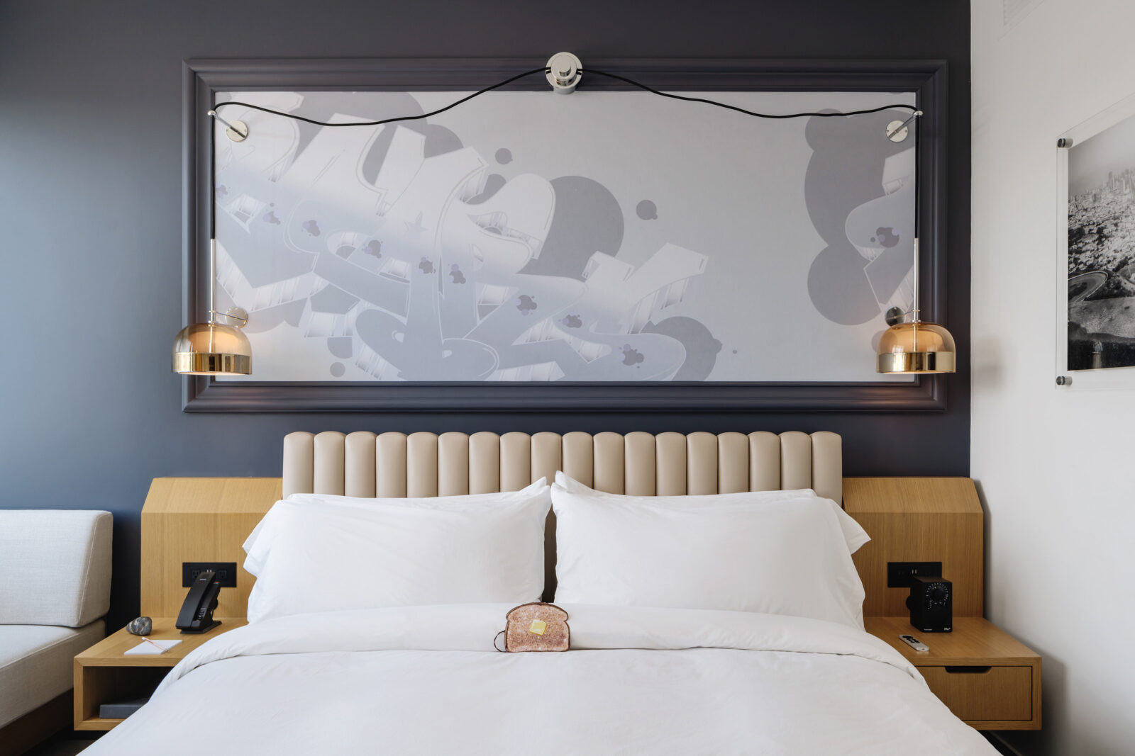 The room features a king-sized bed with a wall-fitted portrait just above it.