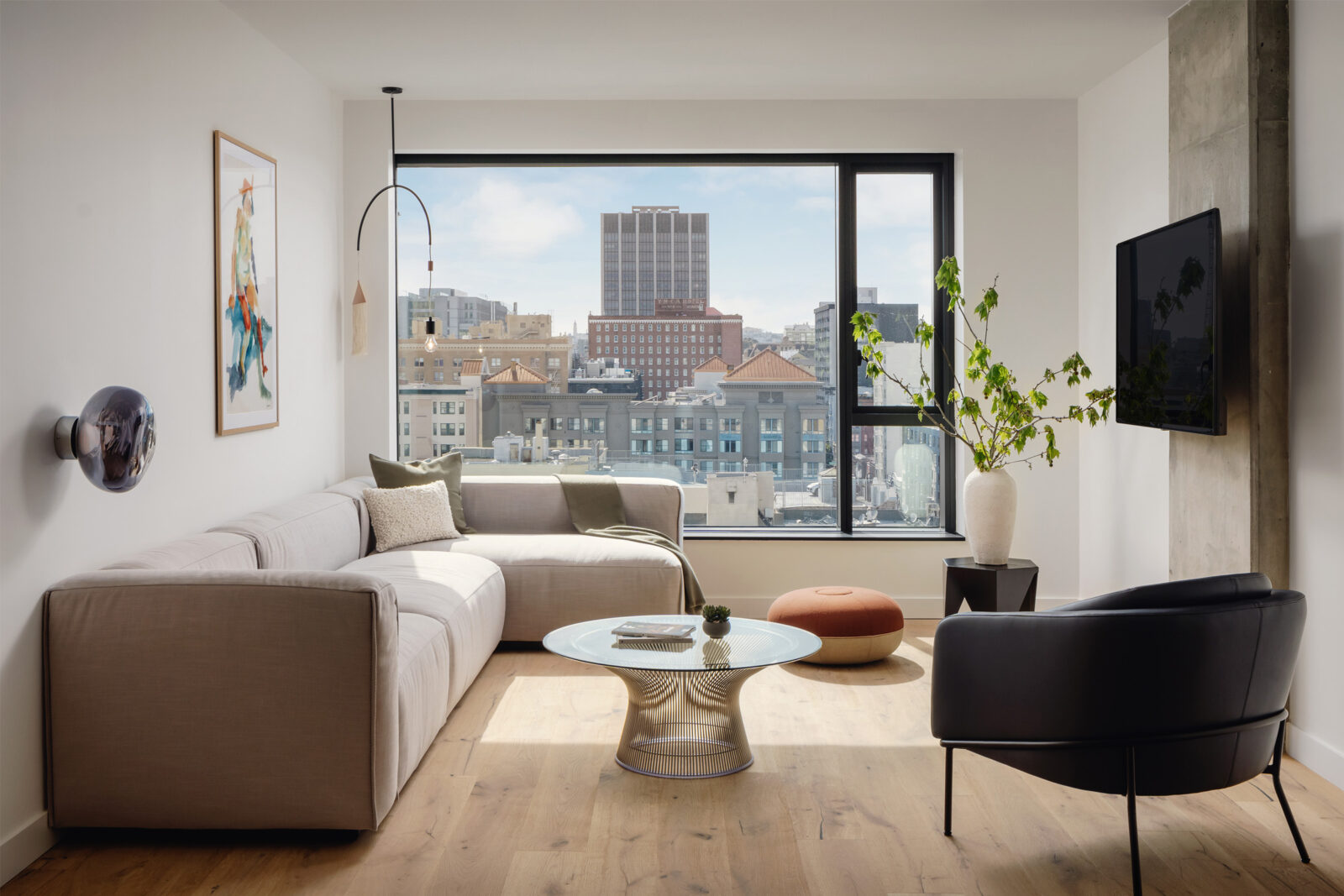 A L-shaped couch positioned near the glass window offers a wonderful view of the city.