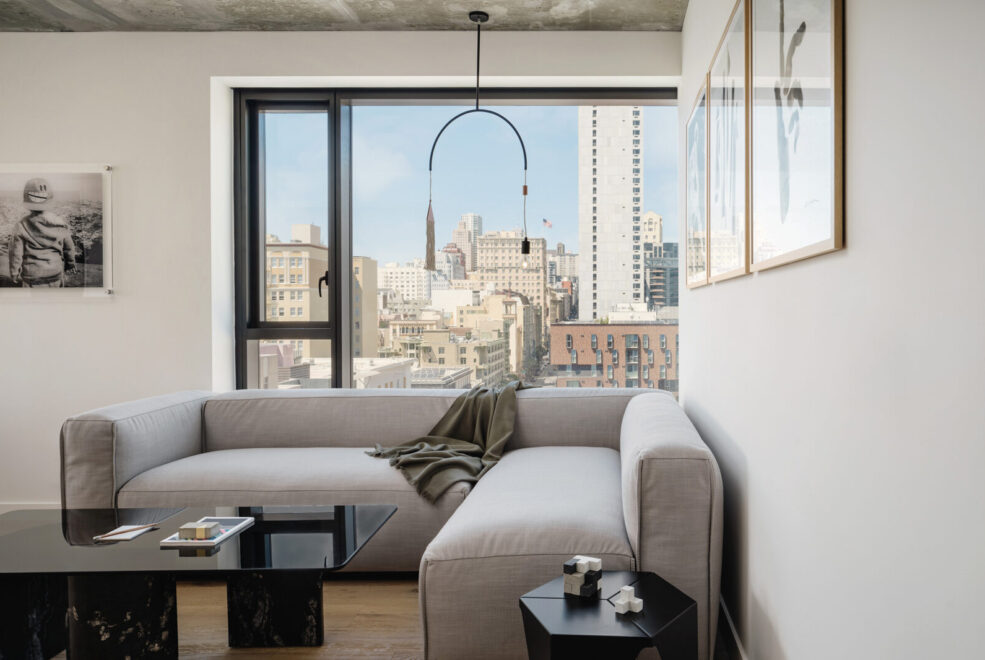 Grey sectional couch in hotel room with a city view