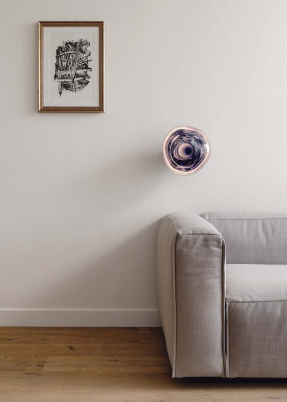 Gray couch with globular wall sconce and framed art