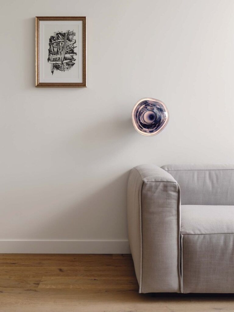 Gray couch with globular wall sconce and framed art