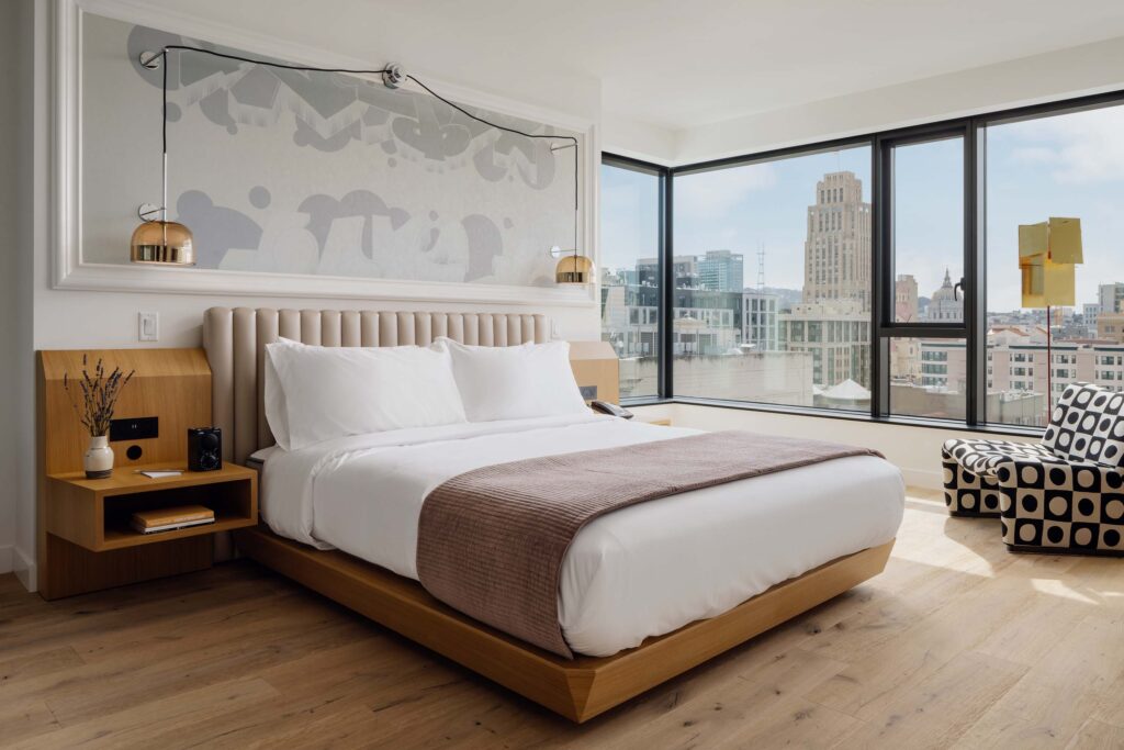 King-sized bed in a hotel room with floor-to-ceiling windows and views