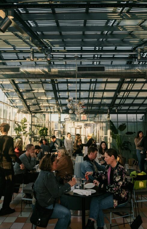 Diners savor their meals beneath a glass-framed rooftop.