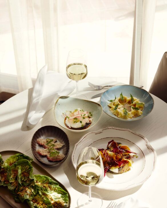 White table with dishes and glasses of white wine