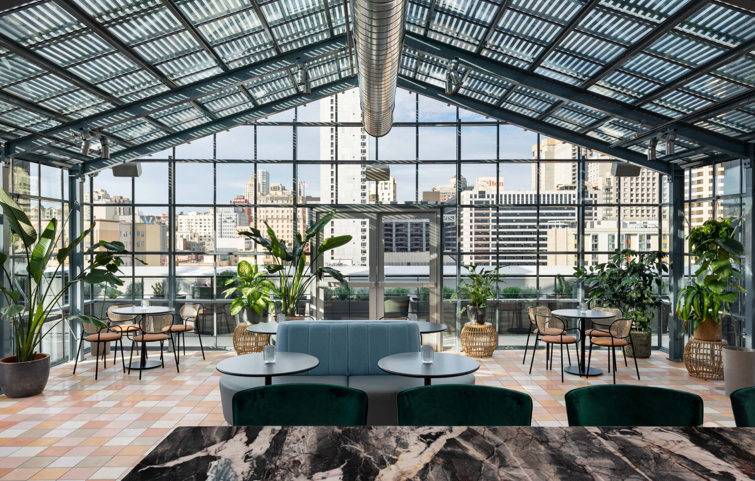 A rooftop solarium bar with furnishings and a breathtaking city view.